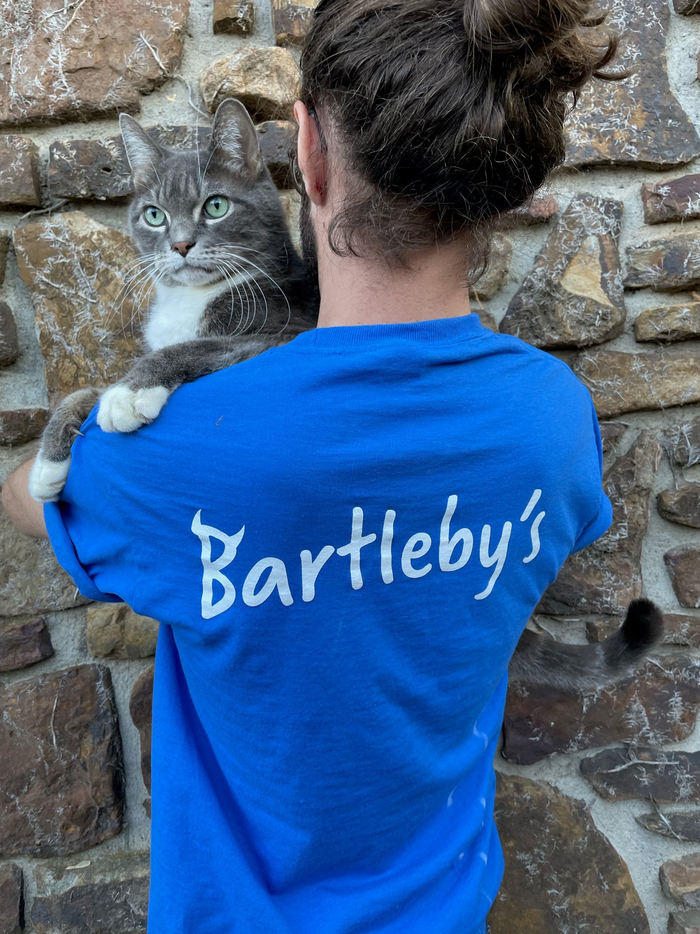 Bring your favorite baby devil, Bartleby, with you where ever you go, tucked in your t-shirt pocket right next to your heart. This blue T-shirt with the devil in the pocket is fun, quirky, and cute, with "Bartleby's" written on the back between the shoulders, allowing you to rep your favorite small woman-owned business. T-shirts ship free!