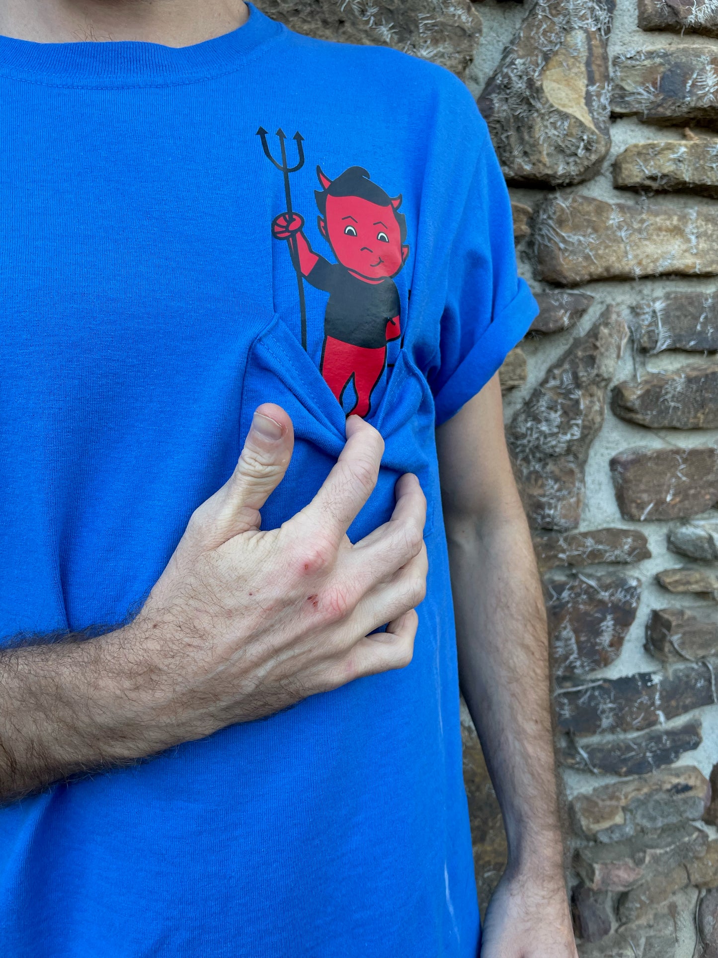 Bring your favorite baby devil, Bartleby, with you where ever you go, tucked in your t-shirt pocket right next to your heart. This blue T-shirt with the devil in the pocket is fun, quirky, and cute, with "Bartleby's" written on the back between the shoulders, allowing you to rep your favorite small woman-owned business. T-shirts ship free!